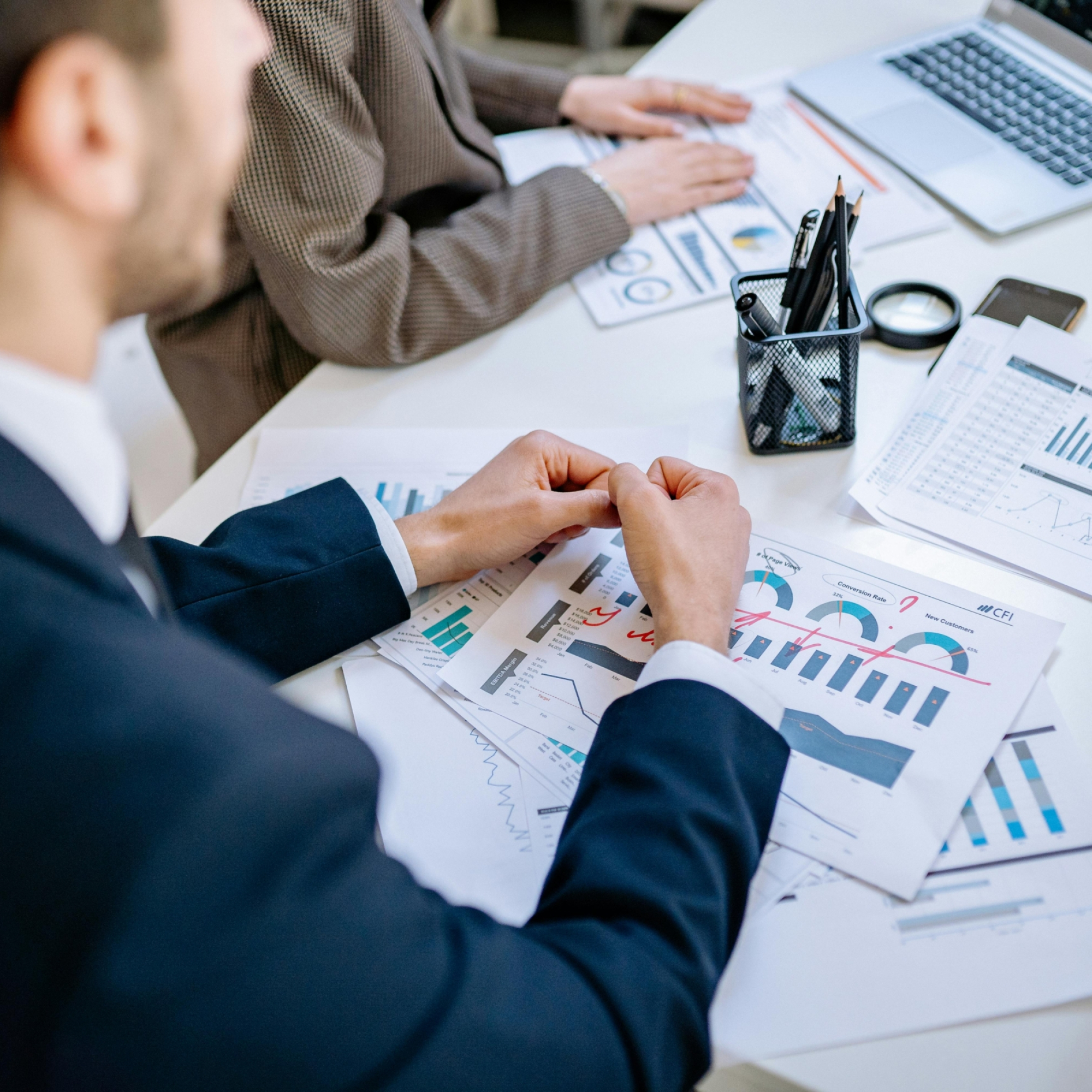 Business team analyzing financial graphs at a meeting table, fostering collaboration in an office environment.